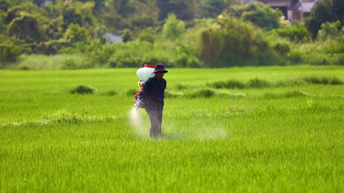 Application by landscape area — The Complete Guide Worker using a backpack sprayer in a green field