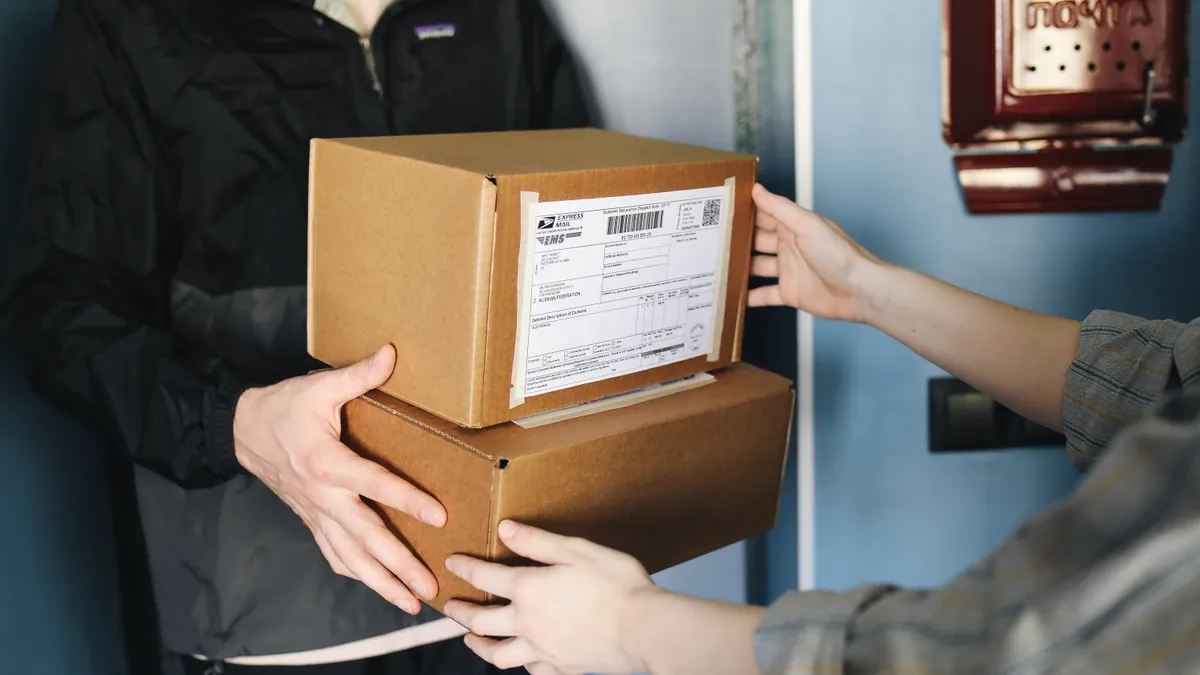 two people exchanging cardboard boxes at a doorstep