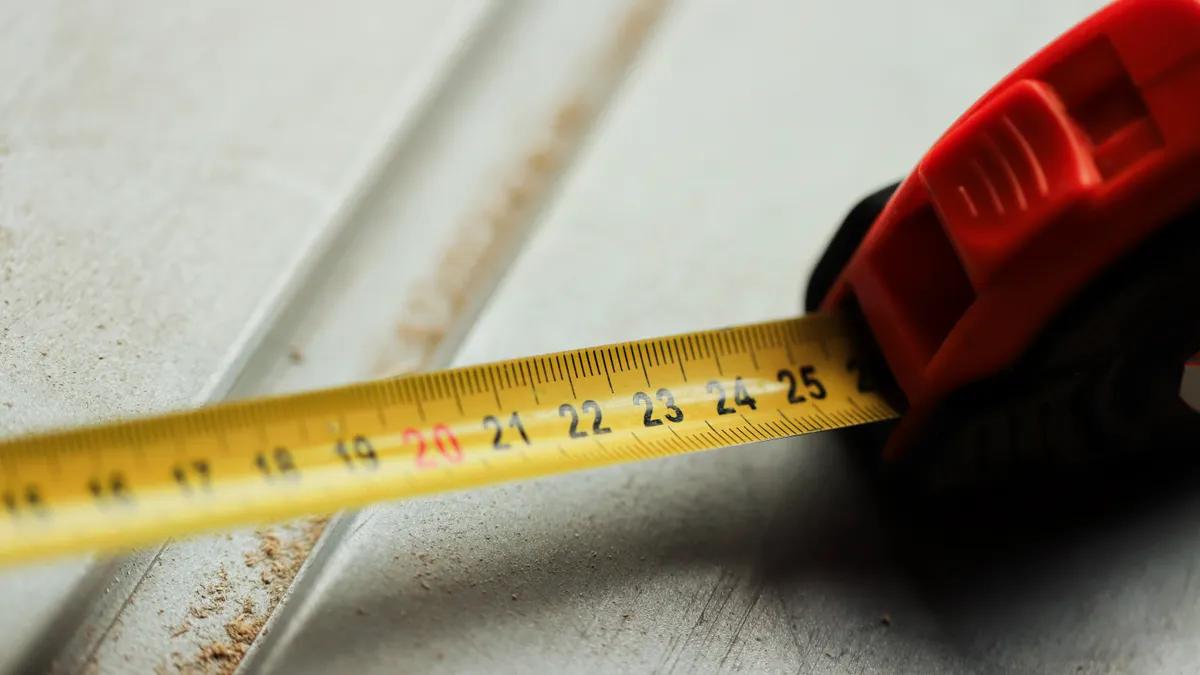 How to Estimate Mulch for Raised Beds and Planter Boxes Tape measure measuring the edge of a board or panel