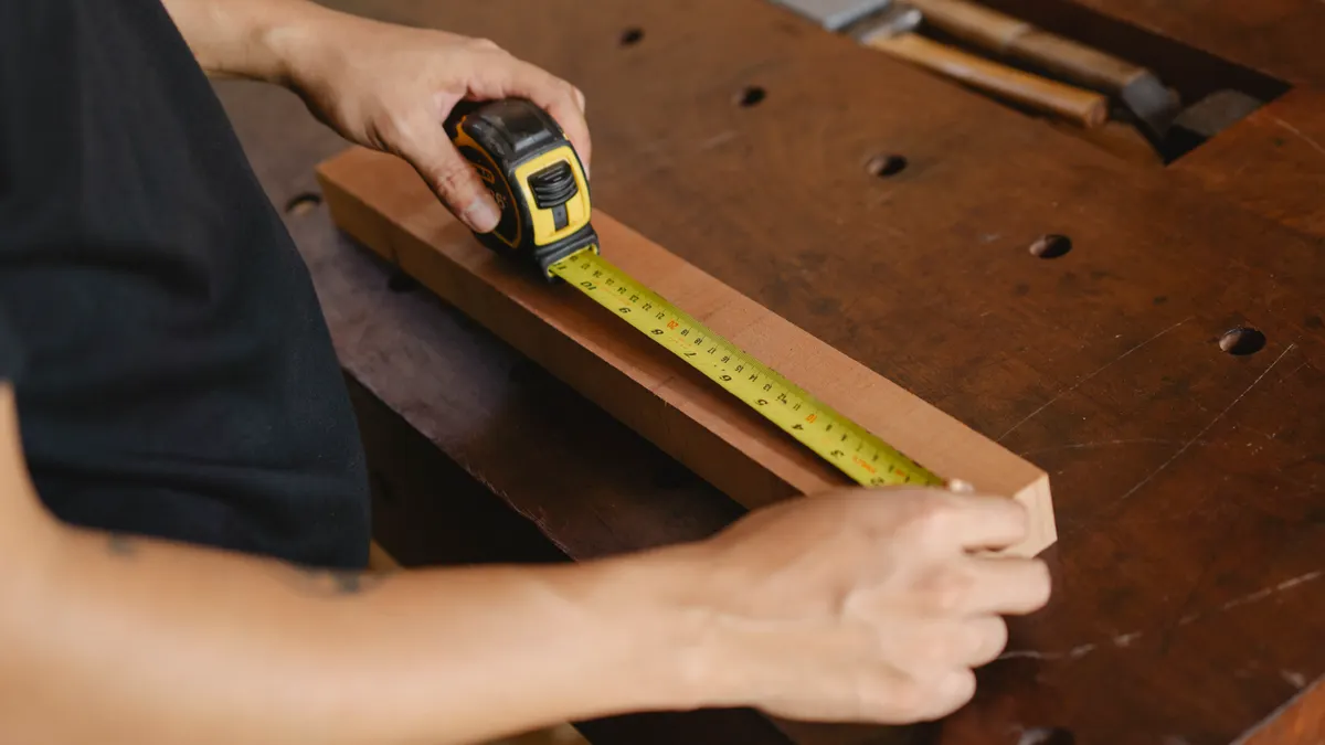 How to Estimate Mulch for Raised Beds and Planter Boxes Person measuring a wood piece on a workbench