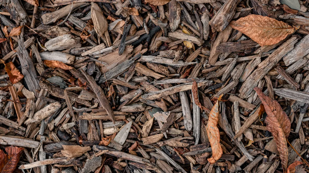 How to Refresh Old Mulch Without Building Up Too Much Depth Brown wood chip mulch with a few leaves