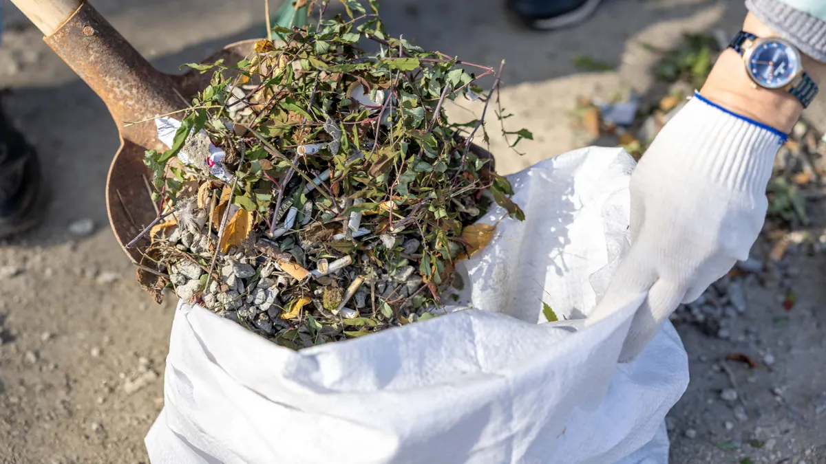 Shovel scooping old yard debris into a bag